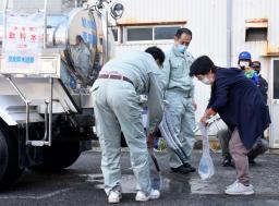 <p>　防災訓練で奈良県の給水車から水を受け取る地元住民（右）＝１４日午前、三重県熊野市</p>