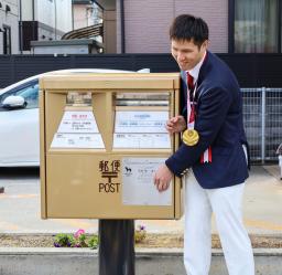 <p>　東京パラリンピック競泳男子での金メダル獲得をたたえ、出身地に設置された金色の郵便ポストに触れる木村敬一選手＝２日午前、滋賀県栗東市</p>