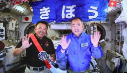 　国際宇宙ステーションからの記者会見で、笑顔で手を振る星出彰彦飛行士（左）と野口聡一飛行士＝４月（ＪＡＸＡの中継映像より）