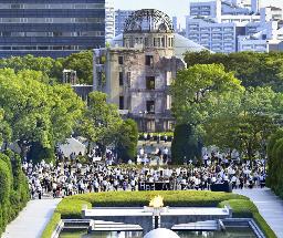 　昨年８月６日、広島市の平和記念公園で黙とうする人たち。後方は原爆ドーム