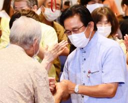 　沖縄選挙区で当選を決め、支持者とタッチする伊波洋一氏（右）＝１１日未明、那覇市