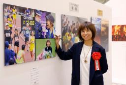 　関西写真記者協会の報道展が開幕し、自身が写った作品にサインする福士加代子さん＝７日午前、京都市