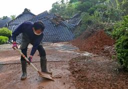 　土砂崩れで本堂が押しつぶされた浄恩寺で、流れ込んだ泥をかき出す男性＝４日午前８時４１分、熊本県益城町