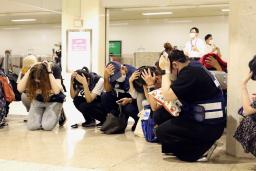 　ミサイル飛来を想定した避難訓練で身を守る姿勢をとる人たち＝４日午前、札幌市