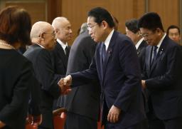 　広島県原爆被害者団体協議会の佐久間邦彦理事長（左）と握手して言葉を交わす岸田首相＝６日午前１０時３０分、広島市