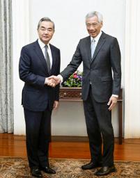 　訪問先のシンガポールでリー・シェンロン首相（右）と握手する中国の王毅共産党政治局員兼外相＝１１日（中国外務省のホームページより、共同）