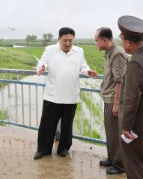 　台風６号で被害が出た北朝鮮東部江原道で、傘も差さずにぬれながら復旧活動を指導する金正恩朝鮮労働党総書記（左）（朝鮮中央通信＝共同）