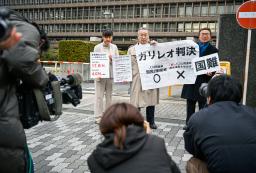 　衆院選の「１票の格差」訴訟の判決を受け、大阪高裁前で「ガリレオ判決」などと書かれた紙を掲げる原告側の升永英俊弁護士（中央）ら＝１２日午後
