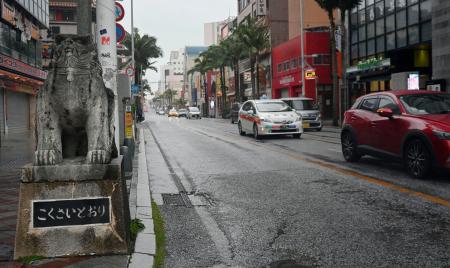 雨と強い風の中、国際通りを走行する車＝１日午前、那覇市