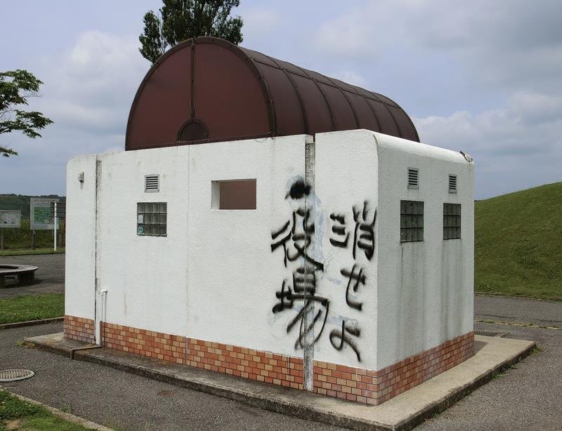 「バンクシー作品？」と騒がれた猿人の落書きが消去された後、最近になって「消せよ役場」という落書きが上から書かれた＝今月３日、印西市山田
