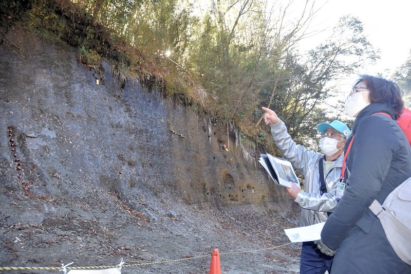 地磁気逆転地層などについて説明する、チバニアンガイド（帽子の男性）＝市原市田淵の養老川沿い