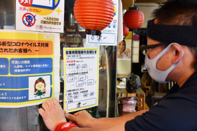 営業時間短縮を知らせる張り紙をする焼き鳥店の店員＝２８日午後４時半、千葉市中央区
