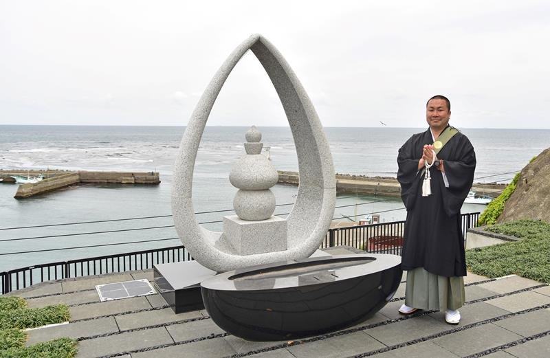 海洋葬「海の弔い」の供養塔前で手を合わせる妙海寺の佐々木住職＝勝浦市
