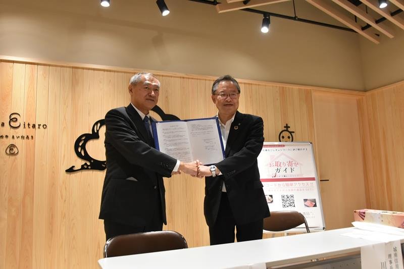 サインした協定書を持つ細田会長（左）と川本理事長＝１５日、都内
