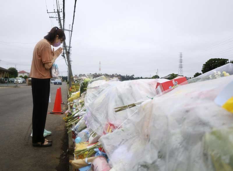 小学生２人が死亡したトラック事故現場の献花台に手を合わせる女性＝３日午後、八街市（共同）