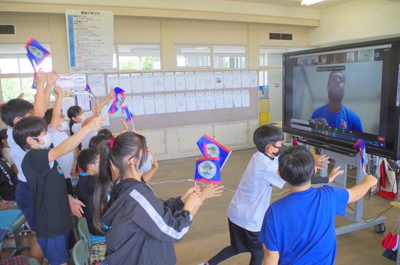 画面越しに国旗を振ってシャウン選手と交流する子どもたち＝横芝光町立光小
