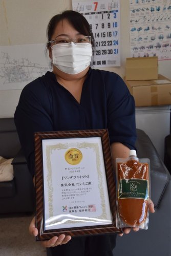 野菜ソムリエサミットの賞状と「ワンダフルトマト」のピューレを掲げる吉野さん＝南房総市