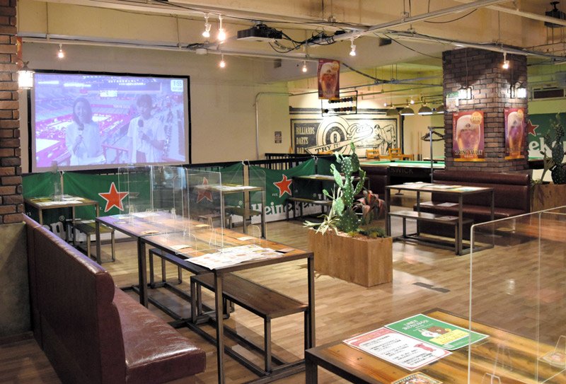 五輪中継をスクリーンで映す「ＳＰＯＲＴＳ　ＢＡＲ　ＧＡＴＥ」。座席には感染対策のアクリル板を設置している＝２６日午後２時ごろ、千葉市中央区
