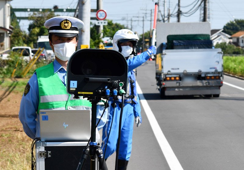 事故が起きた現場で移動式オービスによる速度取り締まりを行う警察官＝３０日午後、八街市八街は