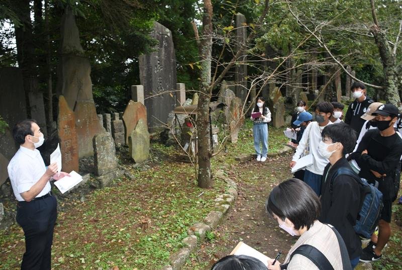 成田山公園で石碑について学芸員の解説を聞く高校生＝成田市