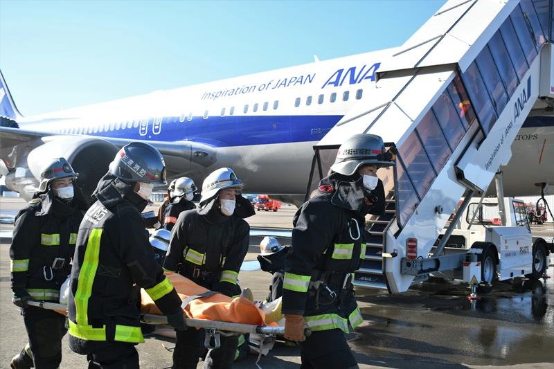 火災が発生した旅客機の中から負傷者を救助する消防隊員＝成田空港
