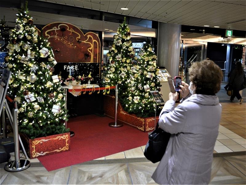 クリスマス装飾に包まれた休止中のストリートピアノ。さっそくスマートフォンで撮影する人も＝船橋市
