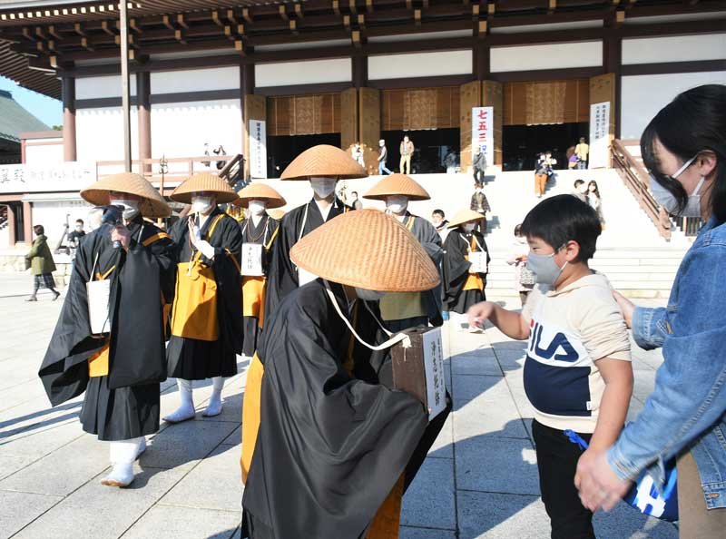 成田山新勝寺の境内で寄付金を僧侶に渡す参拝客＝４日、成田市