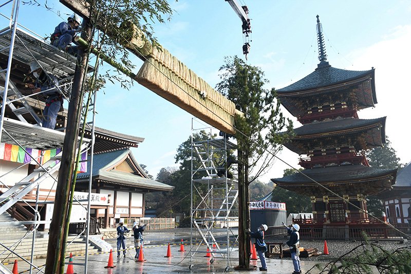 成田山新勝寺の大本堂前に大しめ縄を飾り付ける職員ら＝２５日、成田市