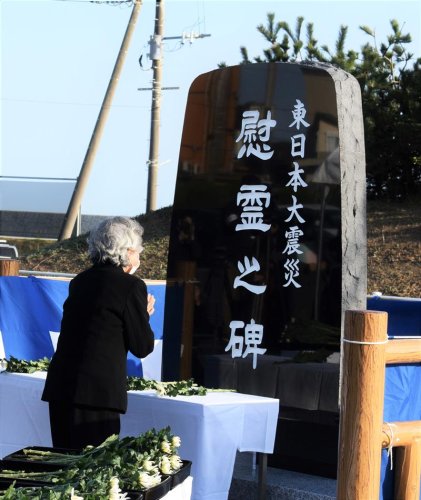 震災から１０年の節目に建立された慰霊碑に手を合わせる遺族＝２０２１年３月１１日、旭市横根