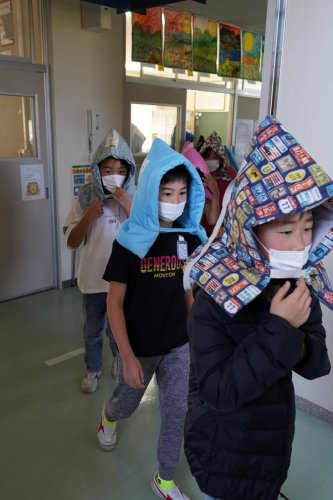 防災頭巾をかぶって避難する児童＝１１日、いすみ市立古沢小
