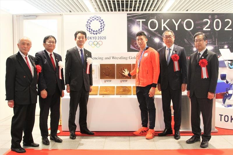 幕張メッセの東京五輪・パラリンピック展示コーナーで自身の手形に手を合わせる見延選手（右から３人目）ら＝２５日、千葉市美浜区
