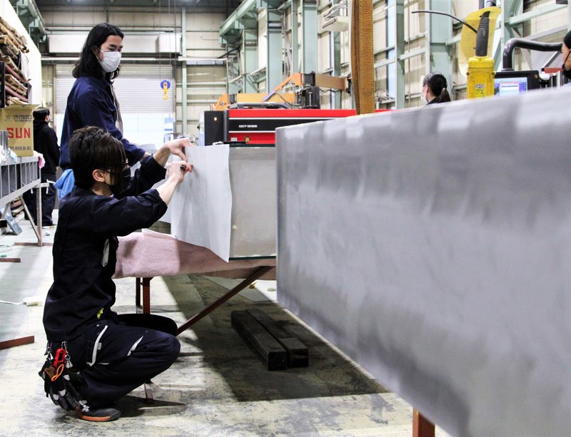 円安によって仕入れ価格の高騰が懸念される鉄材で看板を作成する協同工芸社の従業員ら＝１４日午後５時半ごろ、千葉市美浜区
