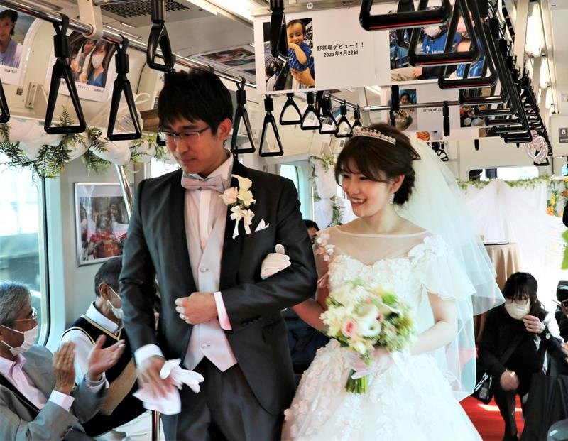 ＪＲ京葉線の車内で結婚式を挙げた鈴木さん夫妻。広告スペースに思い出の写真を並べた（ＪＲ千葉支社提供）
