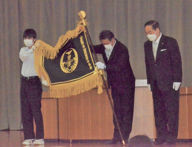 松下市長（右）から学校側に手渡された山武望洋中の校旗＝６日、山武市