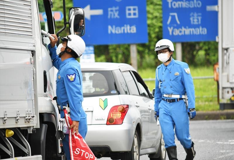高速道路を降りたばかりの運転手を呼気検査する警察官＝２３日午後１時４０分ごろ、富里市
