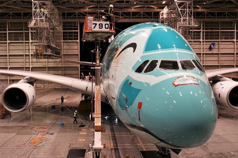高所作業車に乗り、巨大なフライングホヌの機体を洗浄する作業員＝成田空港
