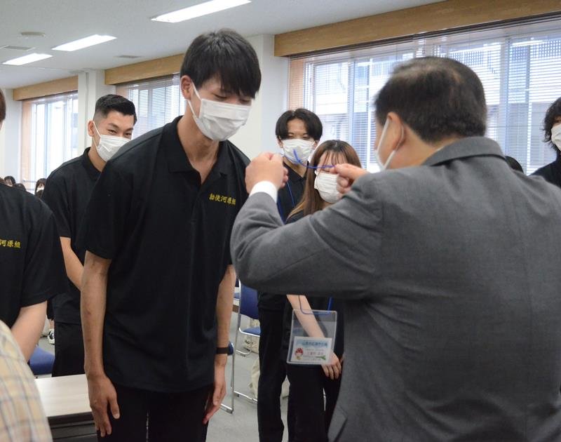 松下市長から「山武市応援学生隊」の名札を渡される千葉商科大人間社会学部の学生ら＝山武市役所
