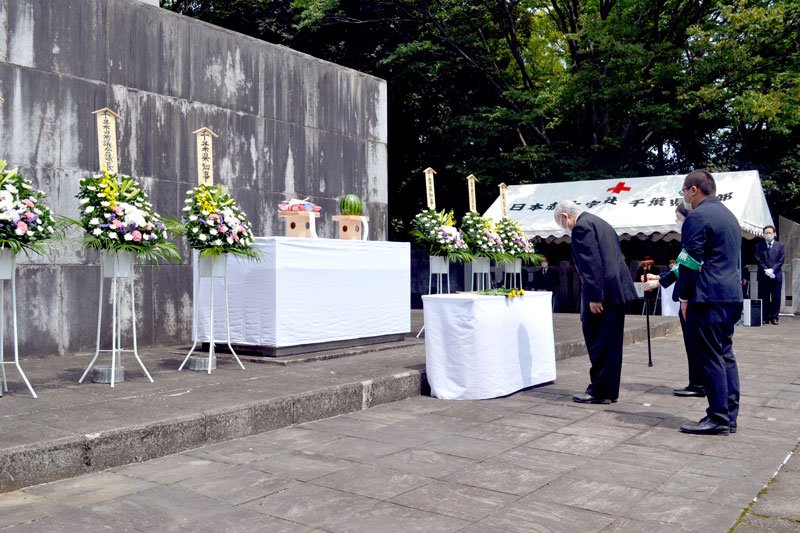 県職員に付き添われ献花する椿会長（左）＝１５日午後０時１５分ごろ、千葉市中央区の県忠霊塔