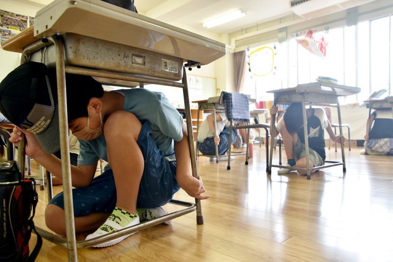 訓練で机の下に頭を隠し、身を守る児童＝１日、館山市立九重小