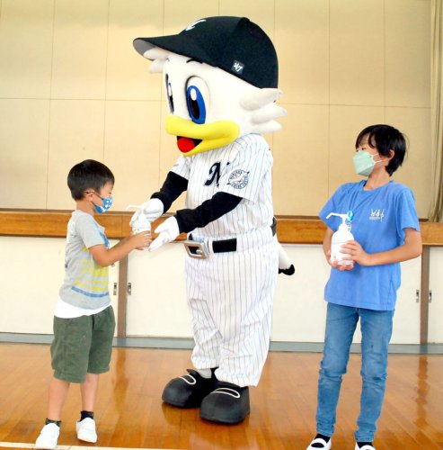 マーくんから消毒液をもらう児童＝茂原市立新治小学校
