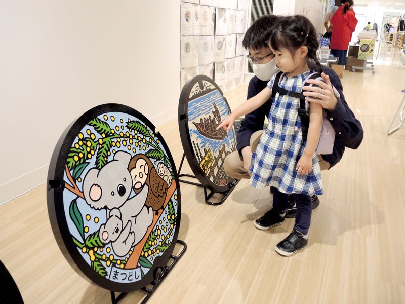 展示されたマンホールに見入る来場者たち＝９日、松戸市
