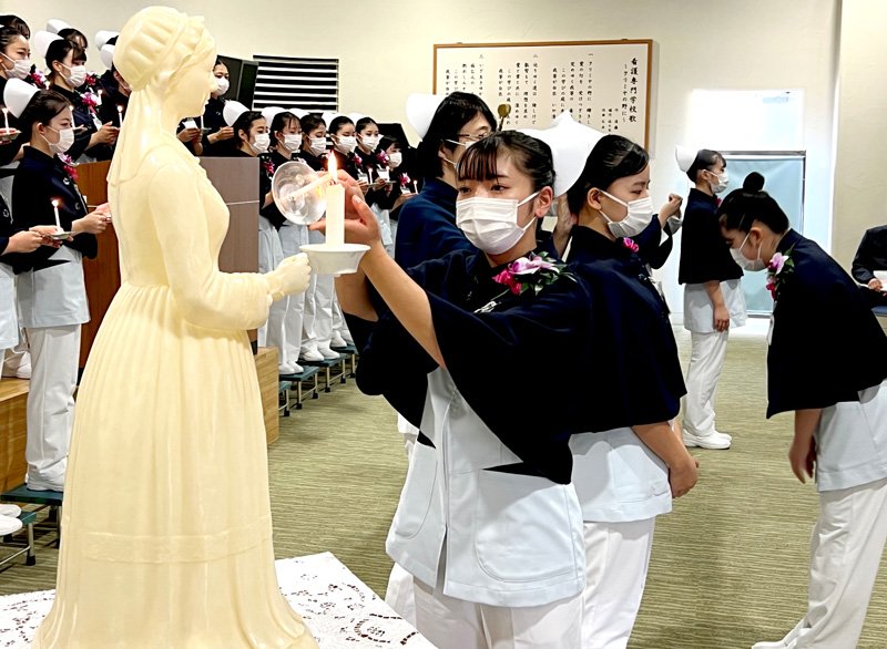 戴帽式でナースキャップを授かり、ナイチンゲール像から灯を受け継ぐ１年生（中央）＝市原市の千葉労災看護専門学校
