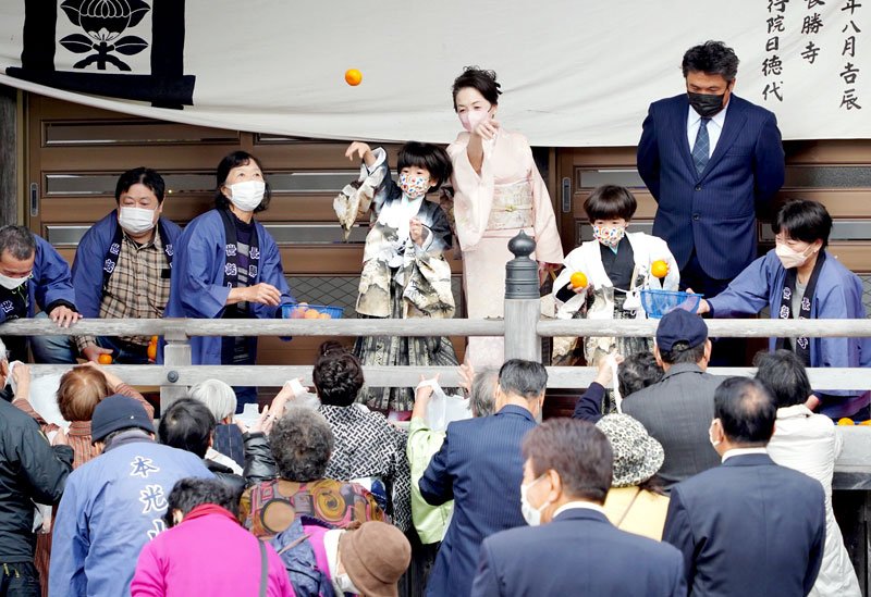 ミカン投げをする七五三の男児ら＝１５日、勝浦市松野の長勝寺
