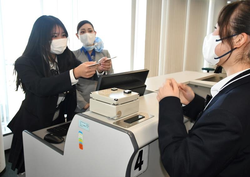 地上係員の指導を受けながら搭乗券の手渡しといったチェックイン業務を体験する高校生＝成田空港
