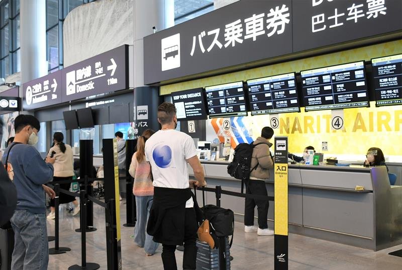 成田空港の国際線到着ロビーでバスチケットを購入する外国人観光客ら＝１２日、成田市
