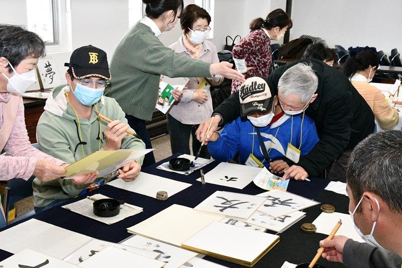 書き方を教わりながら書道に挑戦する外国人ら＝香取市
