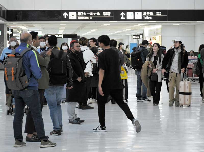 マスクを外した旅客の姿が見られる成田空港の国際線到着ロビー＝１３日、成田市