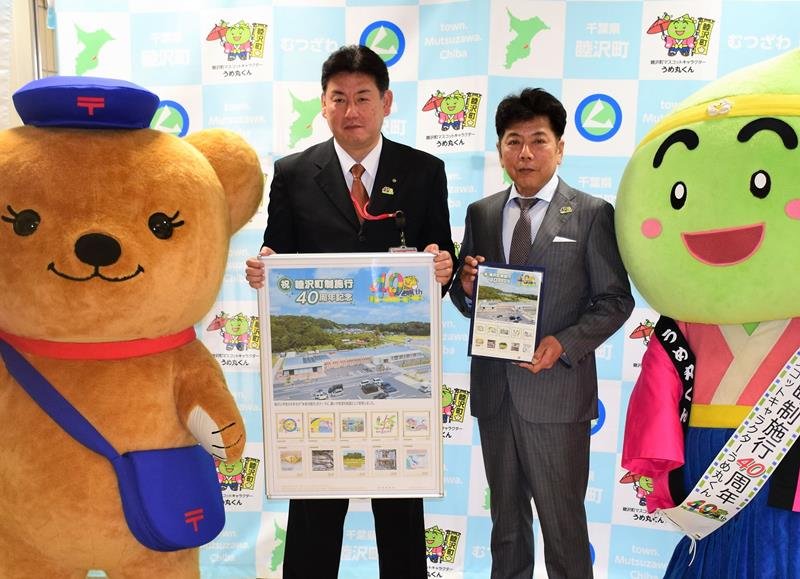 町制施行４０周年の記念切手を持つ田中憲一町長（右）ら＝睦沢町役場

