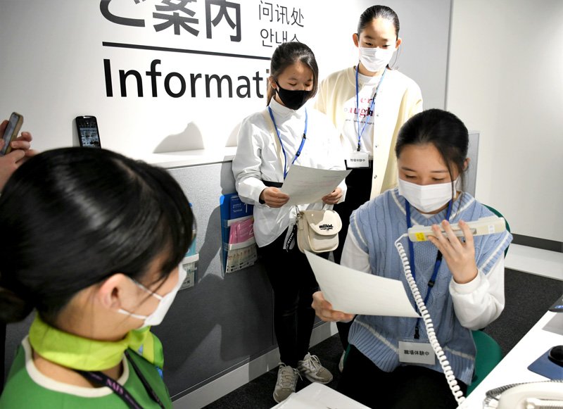 成田空港の案内スタッフに見守られながら館内アナウンスを体験する中学生＝成田市