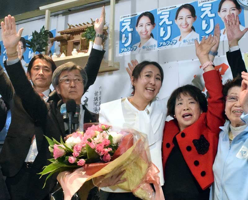 衆院千葉５区補選で当選を決め、万歳する自民の英利氏（中央）＝２４日午前０時２０分ごろ、市川市